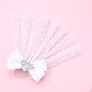 Détail de la pince à cheveux avec nœud en tulle pailleté et couronne en strass