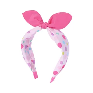 Détail d'un serre-tête rose à oreilles de lapin avec tissu à pois colorés et embouts doux