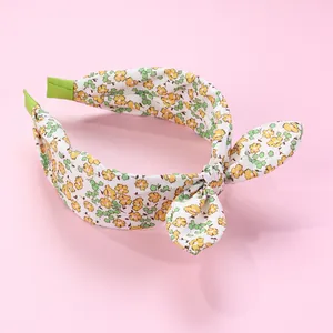 Detail showing floral print headband with rabbit ear bow and green non-slip ribbon ends