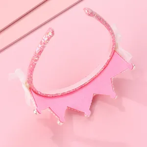 Détail d'un serre-tête rose pour enfant avec couronne, dentelle blanche et perles