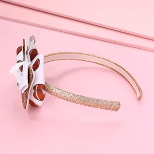 Détail d'un serre-tête rose pailleté avec un nœud à motif rugby pour enfants et sport