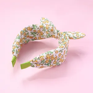 Macro detail of floral fabric headband featuring a top knot bow and green ribbon ends