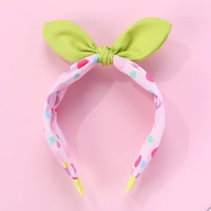 Détail du serre-tête à pois colorés avec nœud vert clair et embouts de confort