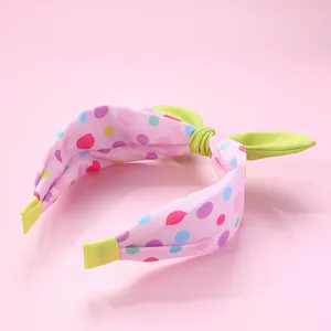 Détail d'un serre-tête rose à pois avec nœud oreilles de lapin vert clair et embouts de protection