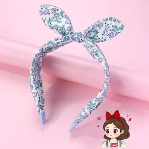 Floral print rabbit ear bow headband with non-slip design on a pink stand