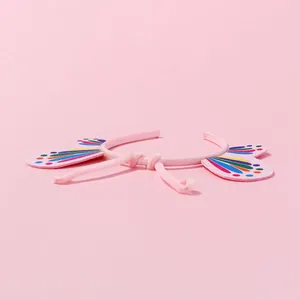 Primer plano de diadema rosa infantil con alas de mariposa y lunares de colores arcoíris