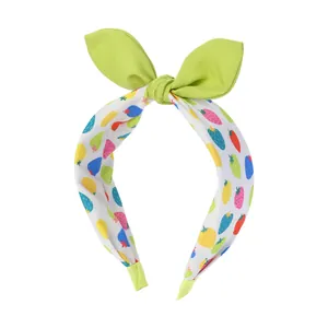 Détail d'un serre-tête en tissu avec imprimés fraises colorés et nœud vert élégant