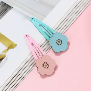 Detail shot of floral hair clips in blue and pink on a soft minimalist background