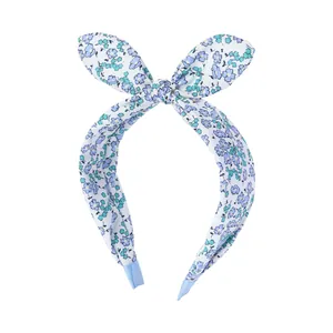 Detail of floral rabbit ear headband with blue small flower pattern on white fabric