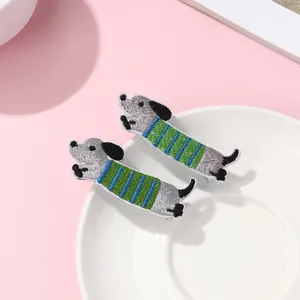 Detailed view of two cartoon embroidered dachshund dog hair clips with striped pattern