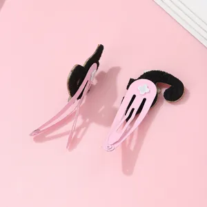 Détail de barrettes BB en métal rose avec oreilles de chat noires et motifs étoiles