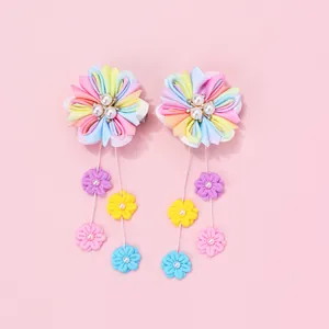 Détail de barrettes à fleurs arc-en-ciel faites main avec pompons et perles nacrées