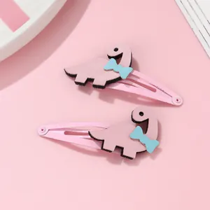 Détail de deux jolies barrettes dinosaures roses avec petits nœuds bleus pour filles