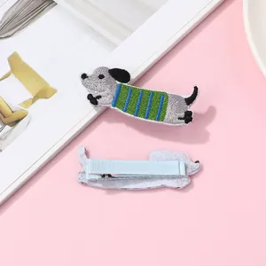 Detail of embroidered dachshund puppy hair clips with blue striped sweaters and metal base
