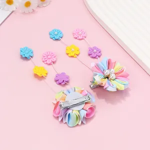 Détail de barrettes fleurs en tissu faites main avec pompons colorés et perles