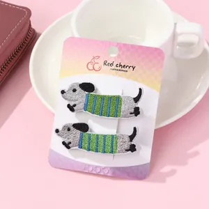 Set of two cute embroidered dachshund puppy hair clips on a decorative display card