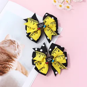 Detail of school-themed bow hair clips with yellow ruler print and ABC blackboard charm