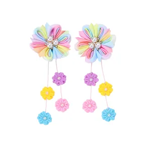 Détail de barrettes à fleurs faites main avec rubans colorés et pompons pendants