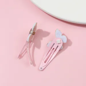 Dettaglio di fermagli per capelli a farfalla rosa con glitter dorati su sfondo rosa