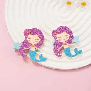 Detail of glitter mermaid hair clips with purple hair and blue tail on white display tray