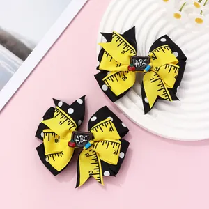Detail of school-themed bow hair clips with yellow ruler patterns and ABC blackboard decor