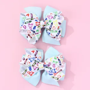 Détail de barrettes à nœuds avec imprimés écoliers sur un fond rose poudré