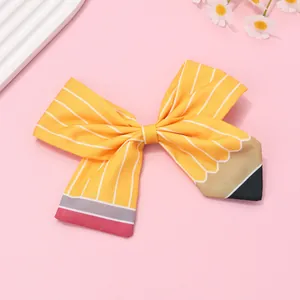 Détail du nœud papillon en tissu motif crayon avec rayures jaunes et gomme rose