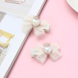 Détail de barrettes noeud en dentelle blanche avec cœur scintillant et petite couronne