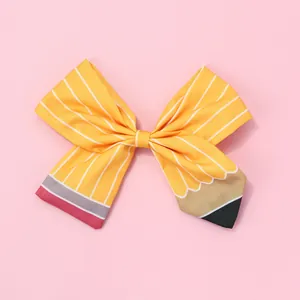 Détail d'un nœud papillon en tissu à motif crayon avec rayures jaunes et pointe rose