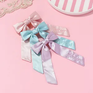 Détail de nœuds de cheveux en satin avec broderie BEST FRIEND FOREVER et longs rubans