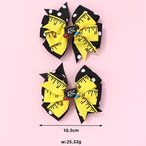 Pair of bow hair clips with yellow ruler print and ABC blackboard charm for school