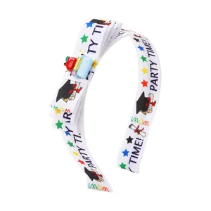 Detail of school-themed bow headband featuring graduation cap prints and resin apple charms
