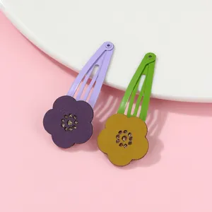 Detail of floral hollow-out hair clips in purple and green with sparkling center accents