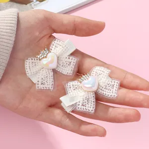 Détail de barrettes en dentelle avec cœurs nacrés et petites couronnes étincelantes