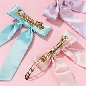 Trois barrettes à nœuds en satin bleu, rose et violet pastel avec des pinces métalliques