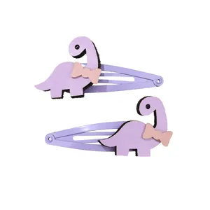 Détail de barrettes dinosaures violet clair avec nœuds roses et finition cuir texturé