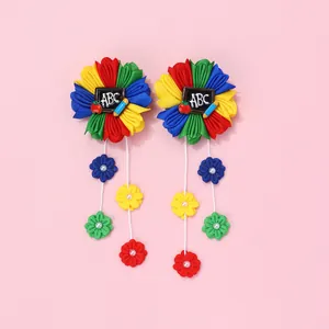 Détail de barrettes fleurs en tissu coloré avec motifs ABC et breloques de perles