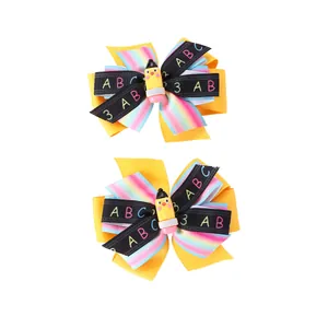Détail de pinces à cheveux style école avec nœuds multicouches et décor crayon