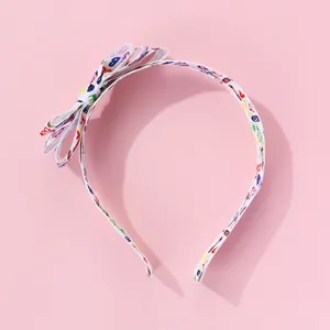 Detail of multi-layered bow headband with colorful cartoon print on white ribbon