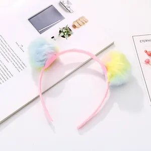 Detailed view of children's pink satin headband with colorful soft pom-poms decor