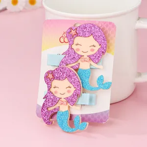 Detail of glitter mermaid hair clips set with purple hair and blue tail on a card