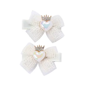 Détail de barrettes en dentelle blanche avec cœur perlé et breloques couronne en strass