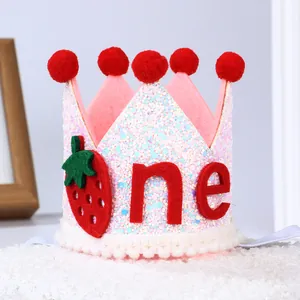 Detail der rosa Glitzer-Babykrone mit roten Bommeln, Erdbeermuster und 'one' Aufschrift