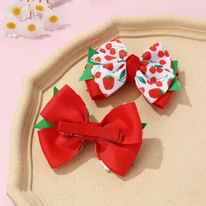 Detail of red strawberry print bow hair clips showing front pattern and metal alligator clip