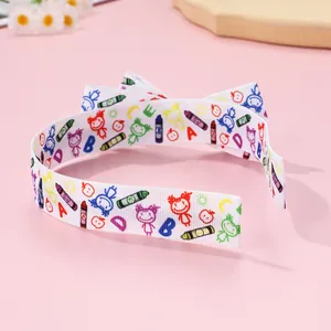 Detail view of white fabric headband featuring colorful cartoon crayons and alphabet patterns