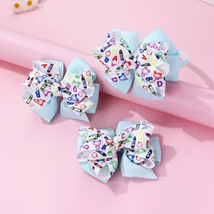 Detail of school-themed bow hair clips with alphabet and crayon prints on light blue ribbon