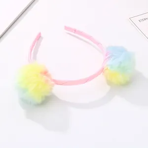 Detailed macro view of colorful pastel faux fur pom-poms on a pink ribbon headband