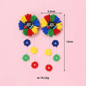 Détail de barrettes fleurs en tissu coloré avec motifs ABC et longs glands fleuris