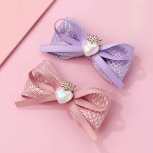 Détail de barrettes nœuds en tissu avec cœurs en cristal et couronnes dorées en rose