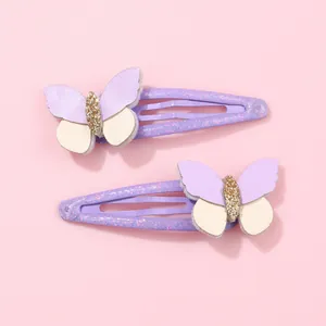 Dettaglio di due fermagli per capelli a farfalla viola con paillettes dorate per bambine